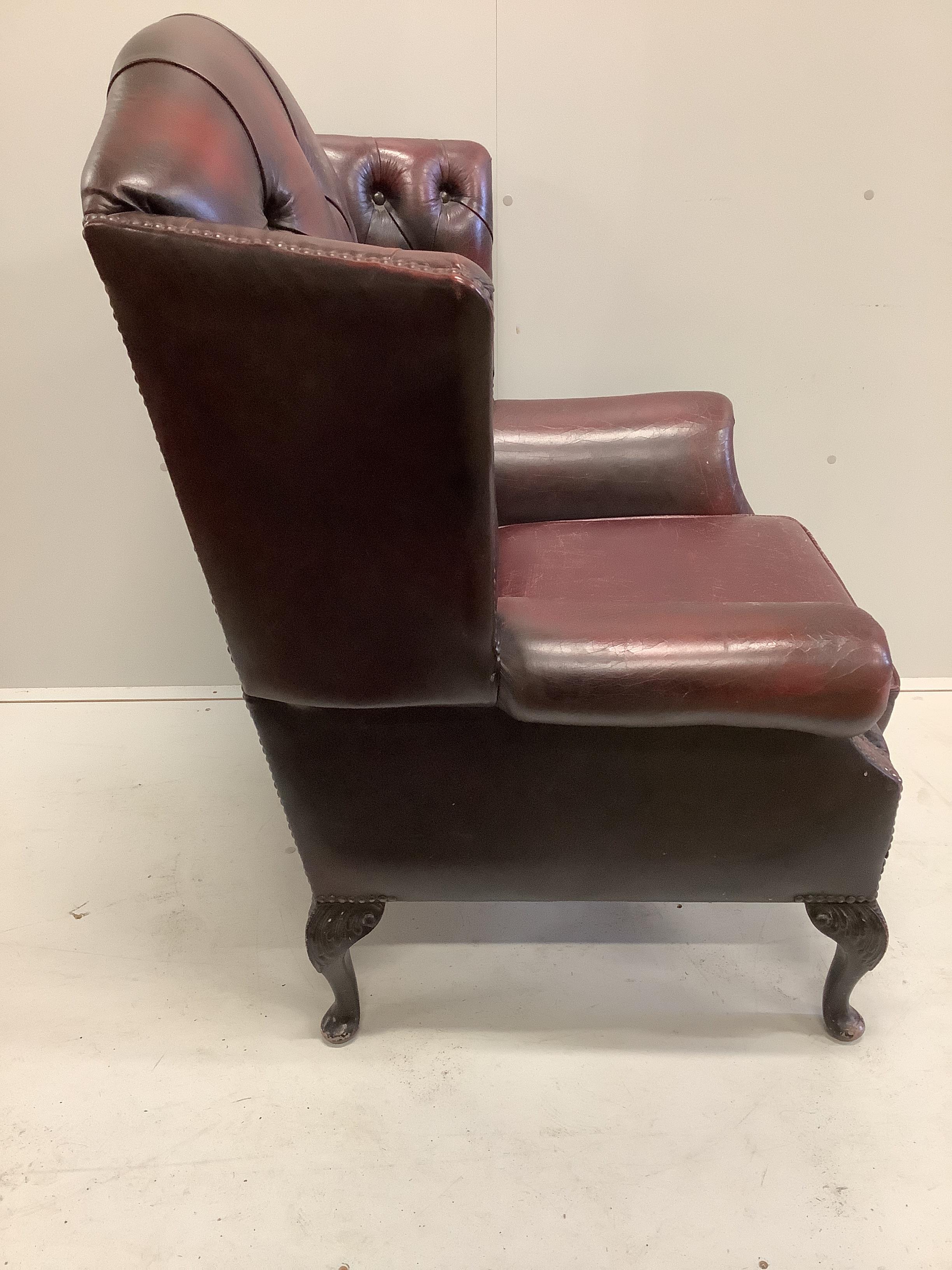 A Victorian style buttoned burgundy leather wing armchair